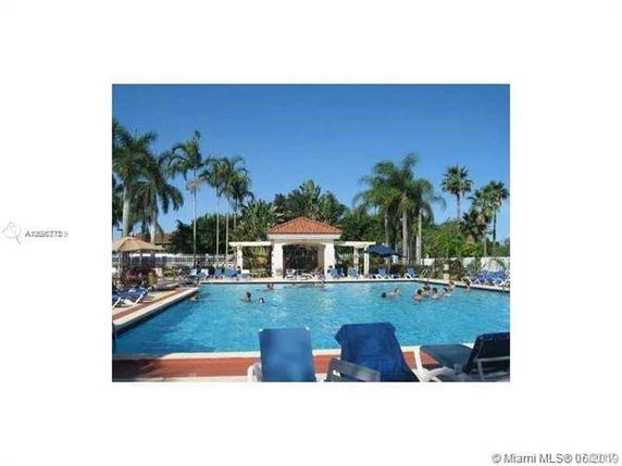 Outdoor swimming pool with sun loungers and palm trees.