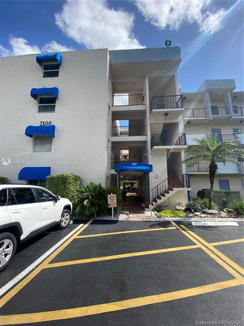 Front view of a multi-story building with blue awnings and open balconies.