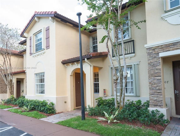 Front view of a two-story house with a beige exterior and brown shutters.