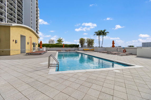 Outdoor rooftop swimming pool area with lounge chairs and umbrellas.