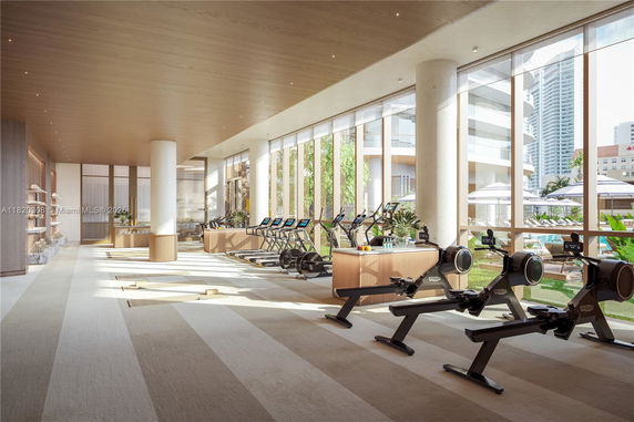 Interior of a modern gym with a row of treadmills and rowing machines.