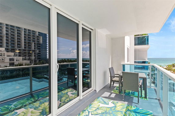 Balcony with chairs and glass railing overlooking the ocean.