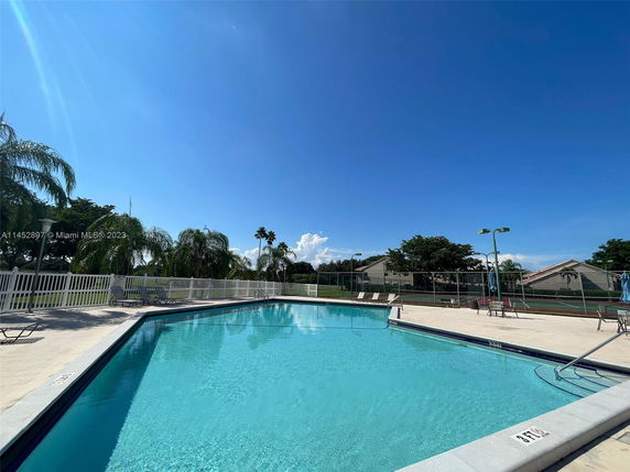 Outdoor swimming pool area with surrounding fence and lounge chairs.