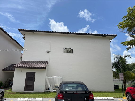 Side view of a residential building with tile roofing and parking spots.
