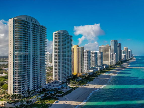 Aerial view of a beachfront with multiple high-rise residential buildings along the coast.