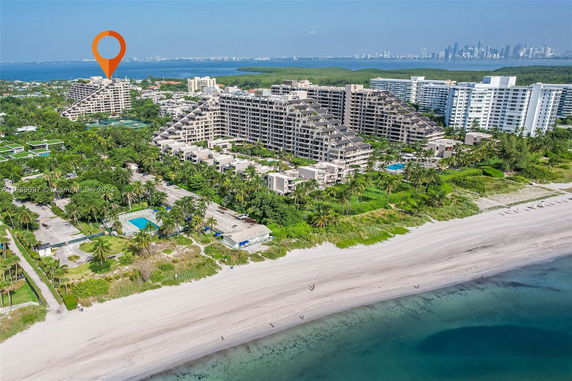 Aerial view of a beachfront area with large residential buildings and surrounding greenery.
