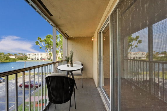 Balcony view overlooking a lake and apartment buildings.