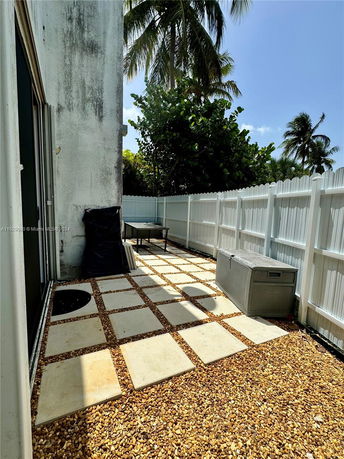 Outdoor area with gravel and stepping stones next to a white fence and building exterior.