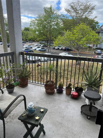 View from a balcony showing a parking area with multiple cars and surrounding trees.