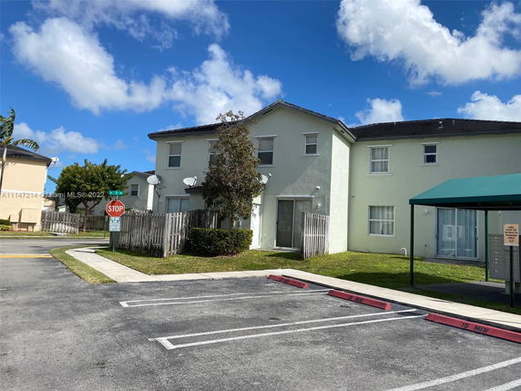 Front view of a two-story house with a small fence and a parking area.