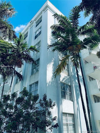 Front view of a multi-story residential building with white exterior and tall windows.