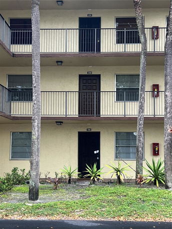 Front view of a multi-story residential building with balconies and doors visible.