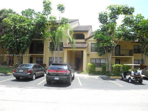 Front view of a multi-story residential building with parking space in front.