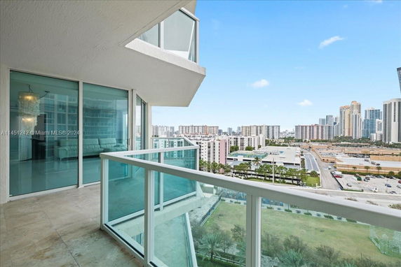 View from a high-rise balcony overlooking a cityscape with buildings and streets.