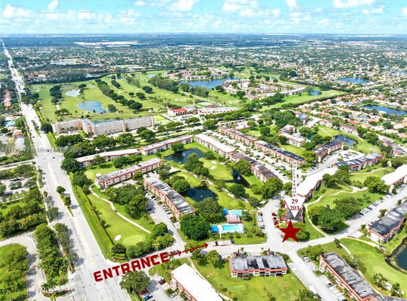 Aerial view of a residential complex with multiple apartment buildings surrounded by greenery and water bodies.