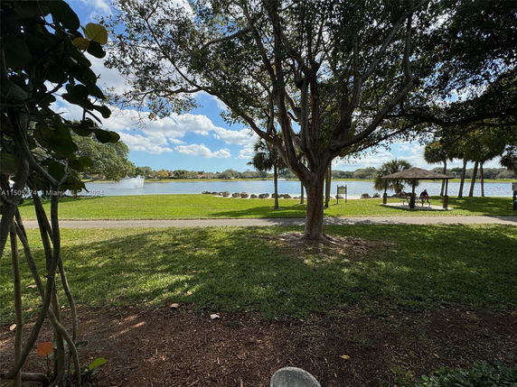 Scenic view of a lake with trees and a bench in a park setting.