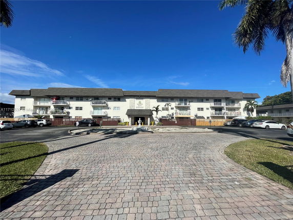 Front view of a multi-story residential building with balconies and parking area.