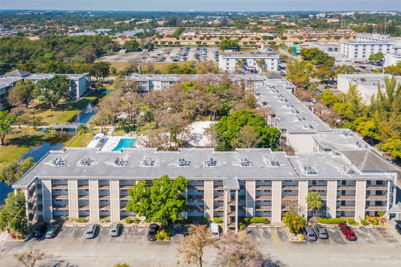 Aerial view of a large apartment complex with a swimming pool and surrounding parking areas.
