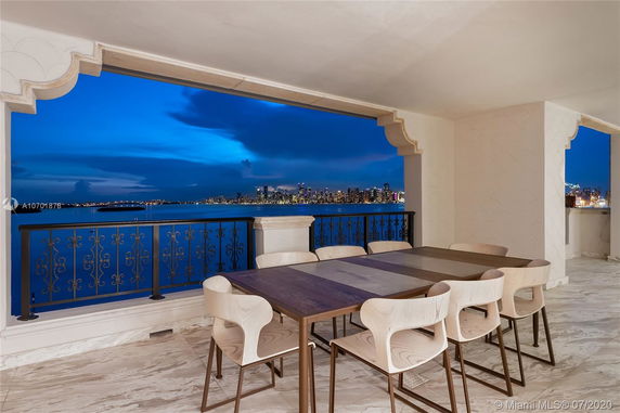 Outdoor dining area with a panoramic view of a city skyline across the water.