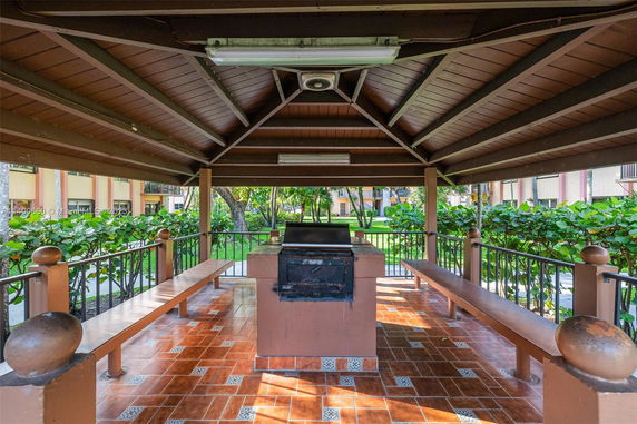 Covered outdoor area with a central grill and seating benches.