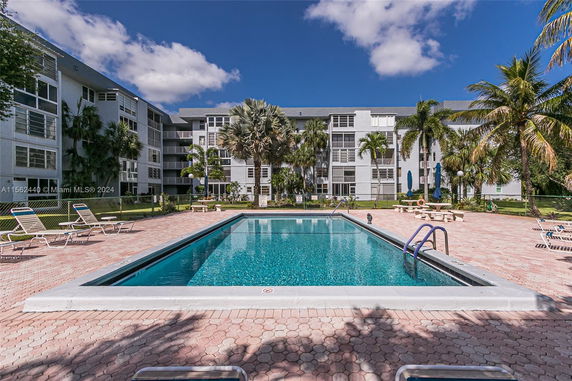 View of an apartment building with a swimming pool in front.