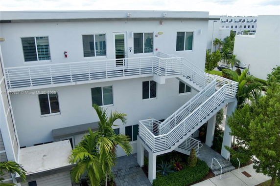 Front view of a modern, two-story building with external stairs and several windows.