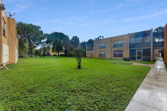 View of a grassy lawn surrounded by two-story buildings.