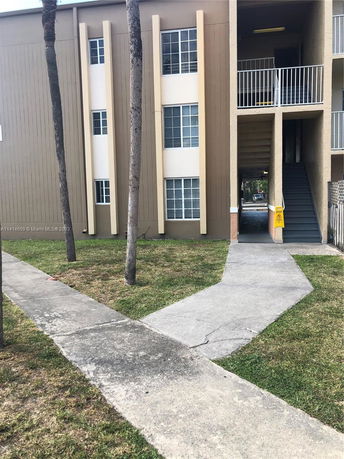 Front view of a multi-story apartment building with windows and a staircase entrance.