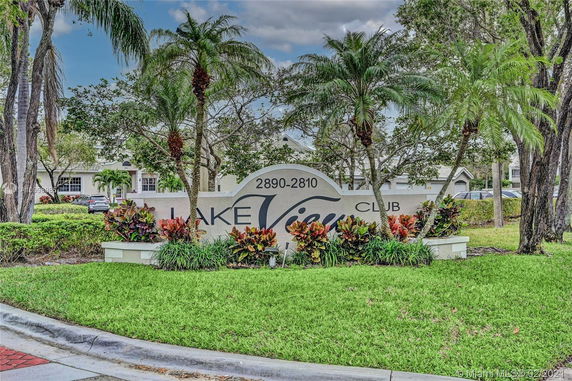 Entrance sign for Lake View Club surrounded by trees and plants.