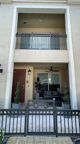 Front view of a two-story house with a balcony and a small fenced patio area.