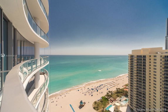 Curved balconies of a high-rise building with ocean and beach view.