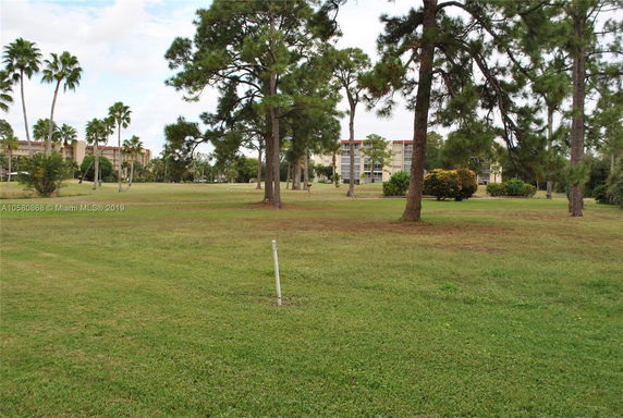 A distant view of apartment buildings surrounded by trees and grassy fields.
