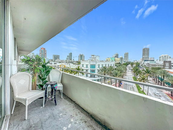 Balcony view overlooking a cityscape with tall buildings and palm-lined streets.