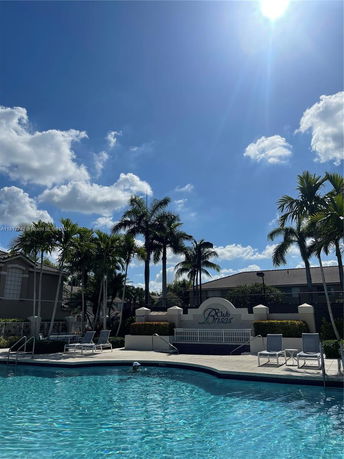 Outdoor swimming pool area with palm trees and lounge chairs.