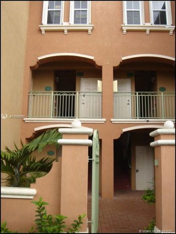 Front view of a multi-story building with balconies and a gated entrance.