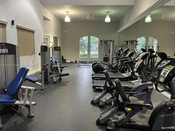 Room equipped with various gym exercise machines and equipment.