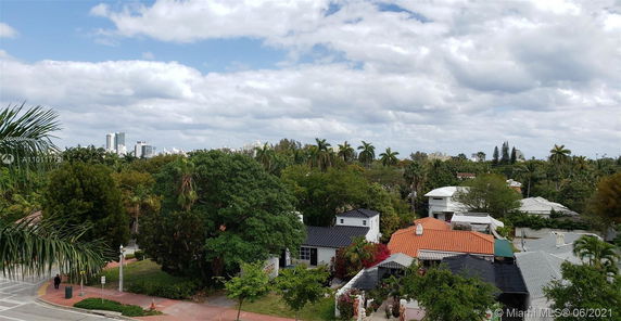 View of residential neighborhood with trees and buildings in the background.