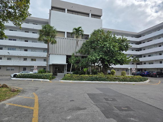 Front view of a multi-story building with a parking area in front.