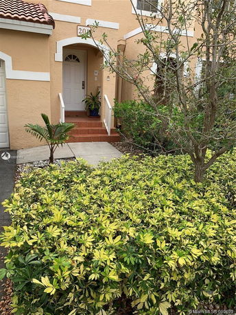 Front view of a house with a small entrance porch and potted plants.