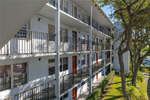 Three-story building with external balconies and red doors.