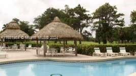 Outdoor swimming pool area with thatched umbrellas and lounge chairs.