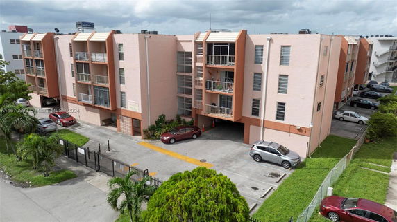 Front view of a multi-story apartment building with balconies and parking area.