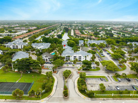 Aerial view of a residential area with multiple buildings, parking lots, and greenery.