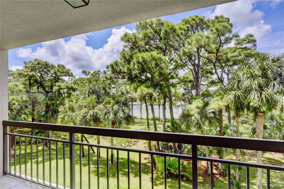 View from a balcony overlooking trees and a body of water in the distance.