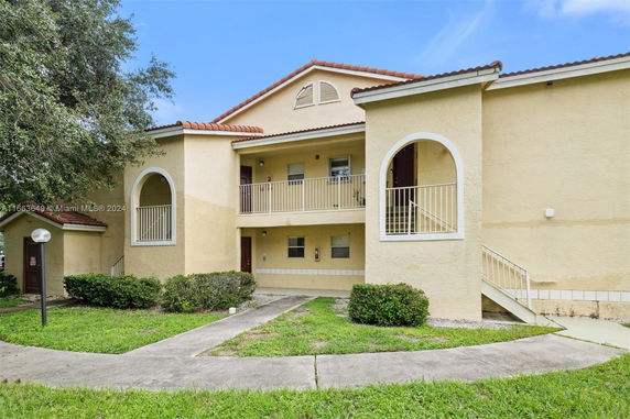 Front view of a two-story residential building with a balcony and arched openings.