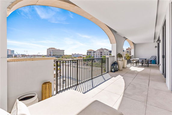 Panoramic view from a balcony with outdoor furniture and a distant view of buildings.
