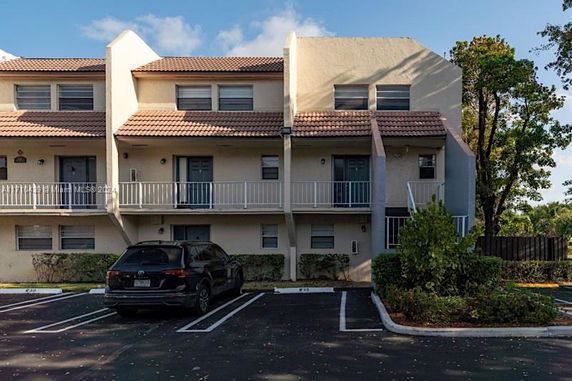 Front view of a multi-story residential building with balconies and parking spaces.