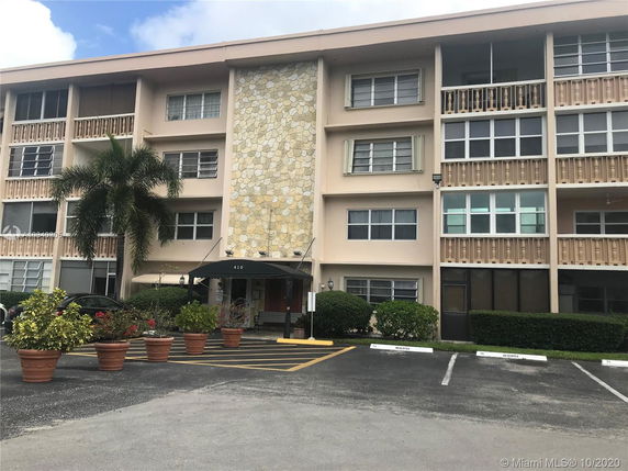 Front view of a four-story building with a stone accent wall and balconies.
