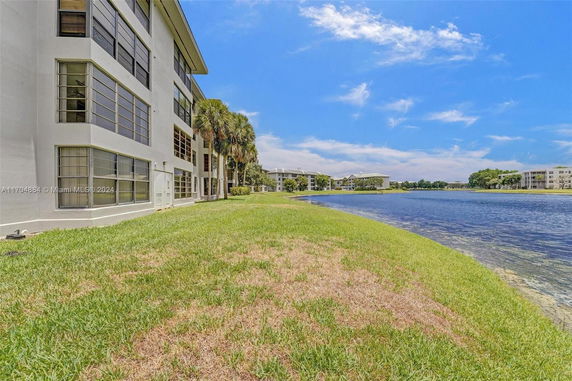 Side view of a multi-story building near a lake with clear skies.