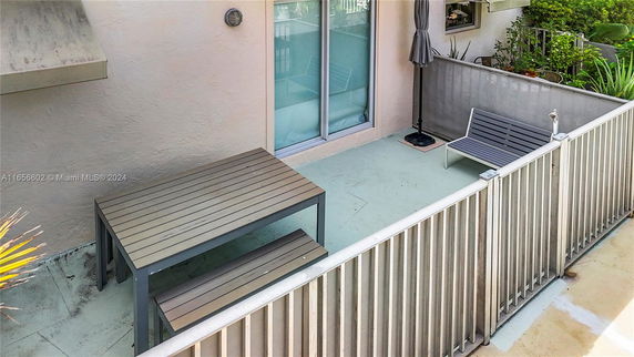 Rooftop terrace with outdoor seating and table, enclosed by a railing.
